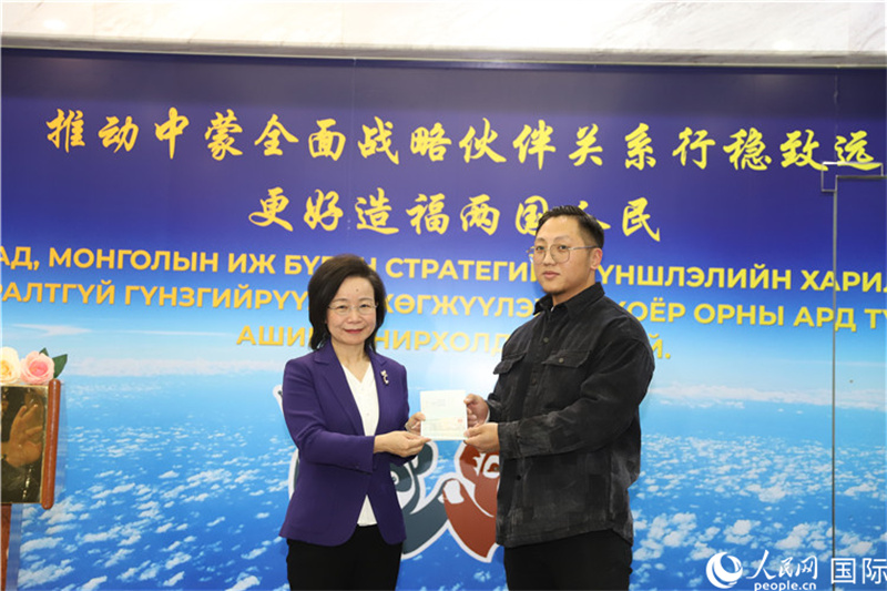 1.11月10日，沈敏娟大使向蒙古国公民巴特巴亚尔（右）颁发本年度第7000份赴华签证。人民网记者 霍文摄